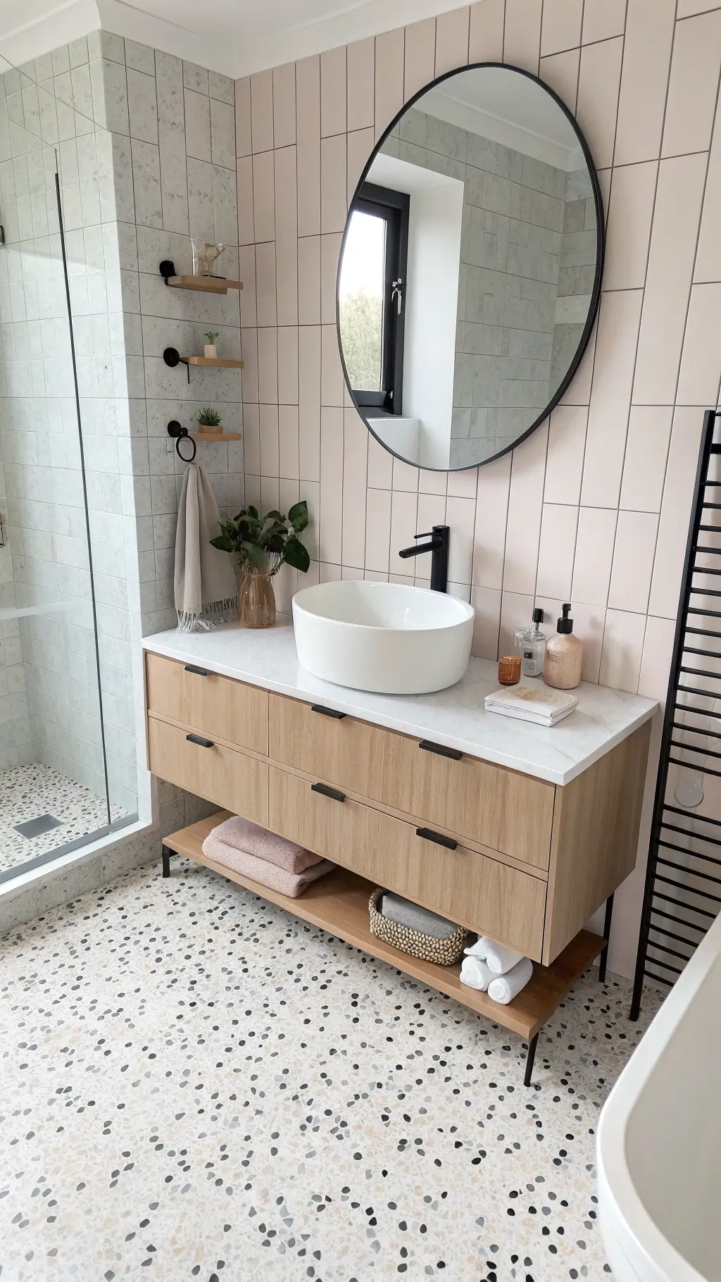 Contemporary Nordic bathroom with terrazzo flooring, white oak vanity, round mirror, vertical white tiles with black grout and matte black fixtures, viewed from bird's eye perspective in soft morning light.